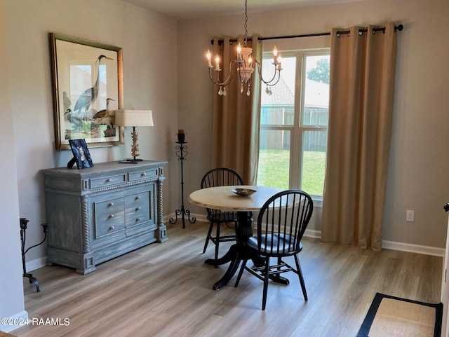 dining area with light wood-style flooring, baseboards, and an inviting chandelier