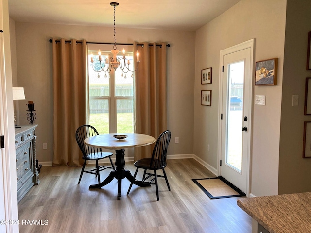 dining room with baseboards, a notable chandelier, and light wood-style flooring