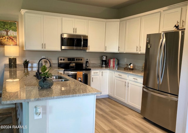 kitchen with white cabinets, appliances with stainless steel finishes, a peninsula, and a sink