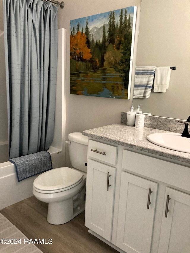 bathroom with vanity, toilet, wood finished floors, and shower / bath combo