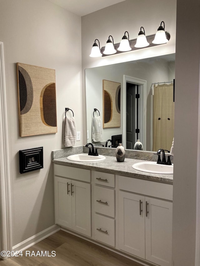 full bath featuring a sink, wood finished floors, and double vanity