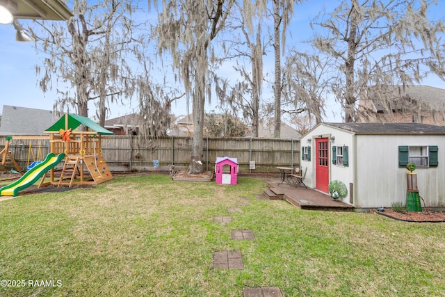 view of yard featuring an outdoor structure, a playground, and a fenced backyard