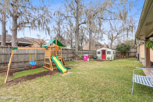 view of yard featuring a storage shed, an outbuilding, a playground, and a fenced backyard