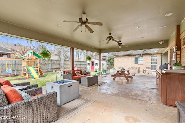 view of patio / terrace with outdoor dining space, a ceiling fan, a fenced backyard, a playground, and an outdoor living space with a fire pit