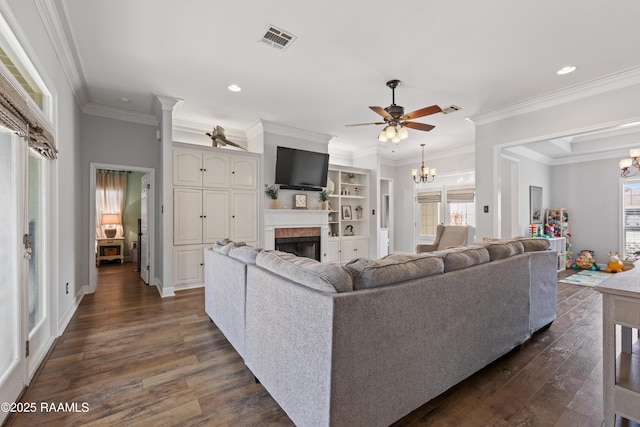 living room with dark wood finished floors, visible vents, ceiling fan with notable chandelier, and a fireplace