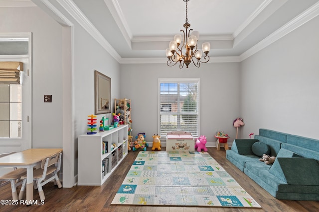 playroom with an inviting chandelier, a tray ceiling, crown molding, and dark wood-style flooring