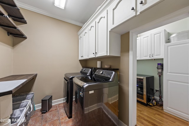 washroom featuring crown molding, baseboards, light wood-style floors, cabinet space, and independent washer and dryer