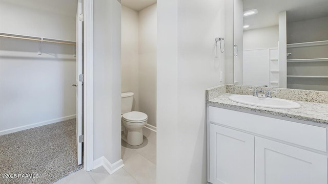 full bathroom featuring tile patterned flooring, a walk in closet, baseboards, toilet, and vanity