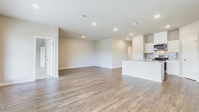 unfurnished living room with light wood finished floors, visible vents, recessed lighting, and baseboards