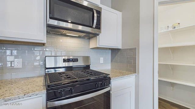 kitchen with light stone counters, white cabinets, and appliances with stainless steel finishes