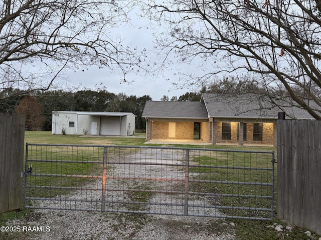 view of front facade featuring brick siding, an outdoor structure, a front yard, and fence