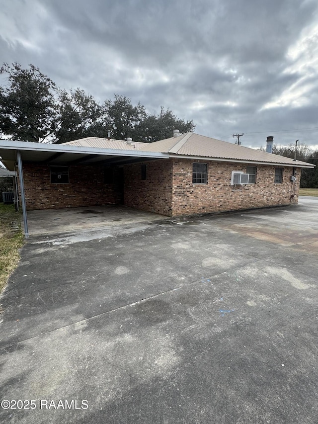 view of property exterior with driveway, a carport, and brick siding