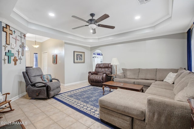 living room featuring ceiling fan, a tray ceiling, light tile patterned floors, and ornamental molding