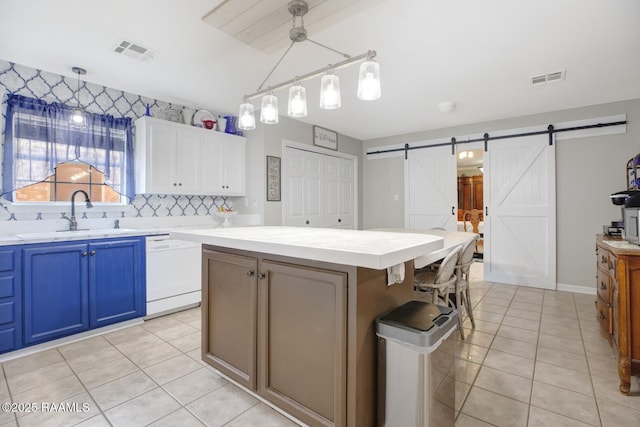 kitchen with a sink, a barn door, dishwasher, and visible vents