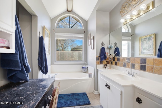 bathroom featuring tile patterned flooring, decorative backsplash, a bath, vanity, and vaulted ceiling