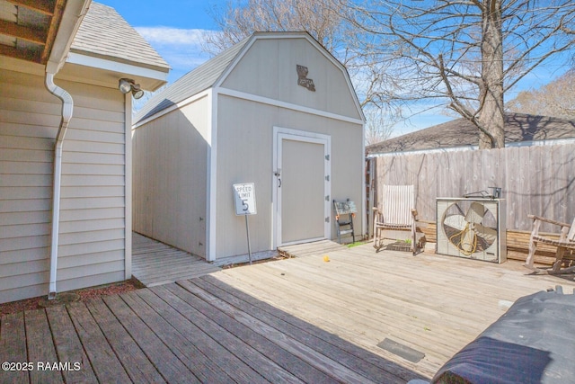 wooden deck featuring a storage shed, an outdoor structure, and fence