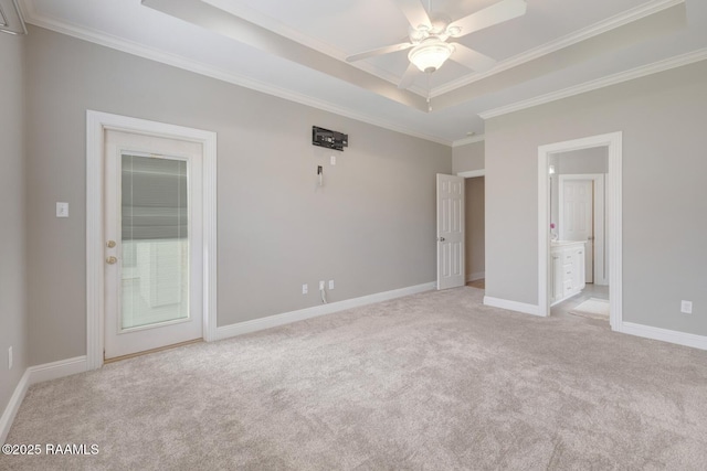 unfurnished bedroom with crown molding, baseboards, light colored carpet, a tray ceiling, and ensuite bath