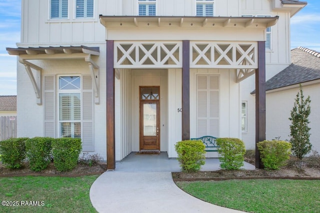 doorway to property featuring board and batten siding and a shingled roof