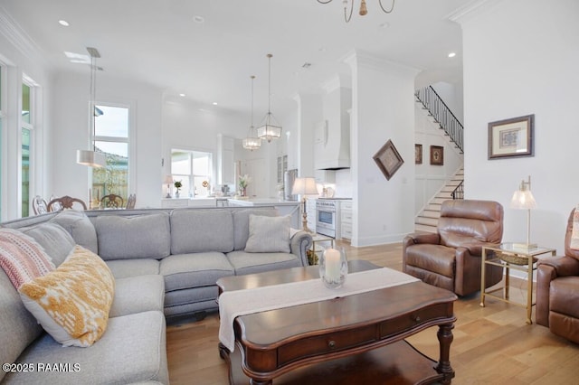 living area featuring light wood-type flooring, ornamental molding, recessed lighting, a chandelier, and stairs