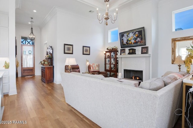 living area with light wood-style flooring, plenty of natural light, a fireplace, and a chandelier