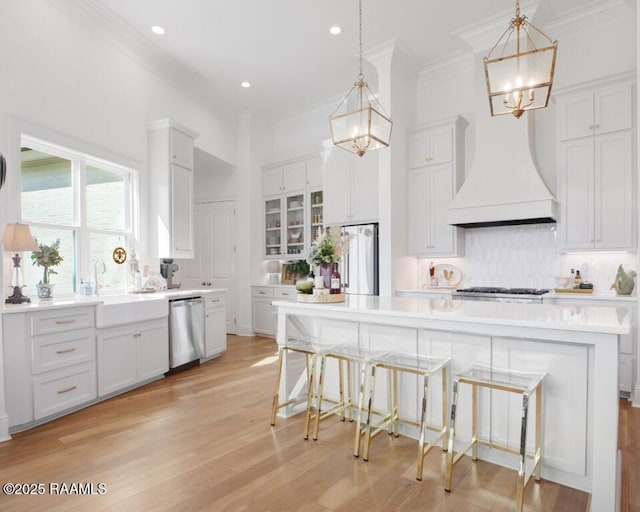 kitchen featuring backsplash, premium range hood, an inviting chandelier, stainless steel appliances, and a sink