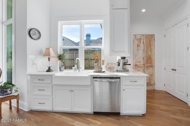 kitchen featuring dishwasher, decorative backsplash, white cabinetry, and a sink