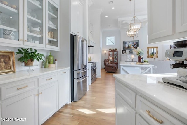 kitchen with hanging light fixtures, glass insert cabinets, light wood-style floors, white cabinetry, and high quality appliances