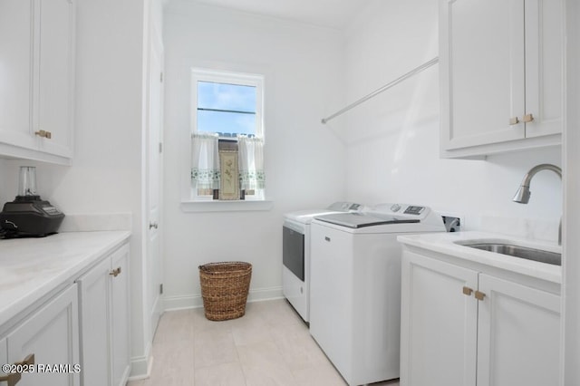 laundry room featuring separate washer and dryer, cabinet space, baseboards, and a sink