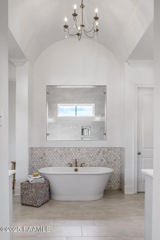 bathroom with a soaking tub, an inviting chandelier, and vaulted ceiling