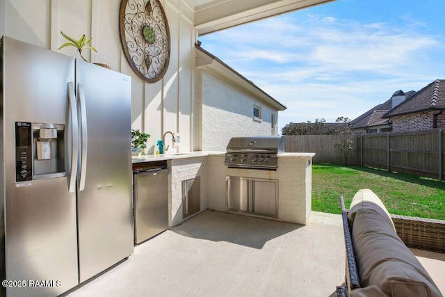 view of patio / terrace featuring area for grilling, a grill, a fenced backyard, and a sink