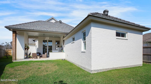 back of house featuring a patio, a lawn, brick siding, and fence