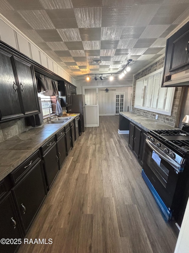 1107 Railroad St, Pine Prairie, LA 70576 - kitchen featuring wood finished floors, gas range oven, dark cabinets, and a sink