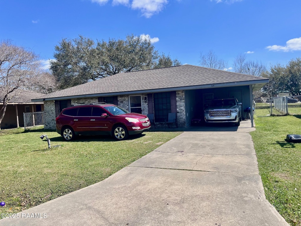 view of front of house featuring an attached carport, driveway, a shingled roof, and a front yard