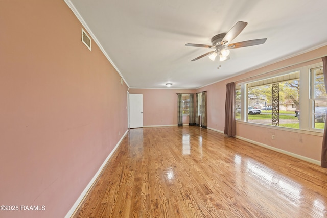 spare room with baseboards, light wood-style floors, ornamental molding, and a ceiling fan