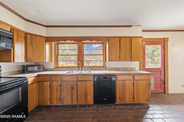 kitchen with tile counters, ornamental molding, brown cabinetry, black appliances, and a sink