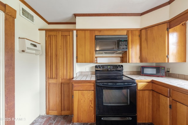 kitchen with visible vents, brown cabinets, black appliances, ornamental molding, and tile countertops