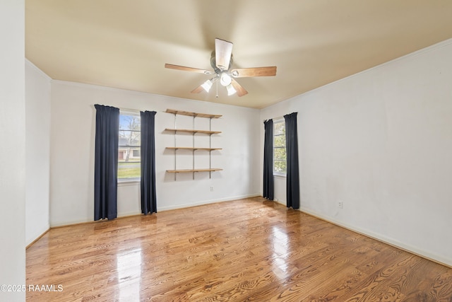 unfurnished room featuring baseboards, crown molding, a ceiling fan, and wood finished floors