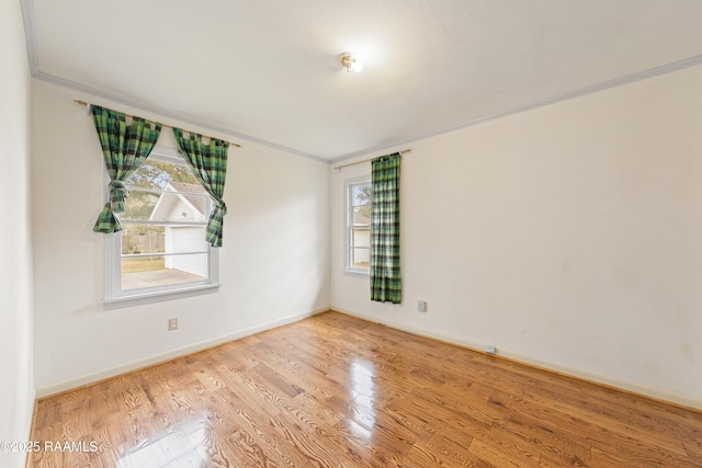 spare room with ornamental molding, baseboards, and wood finished floors