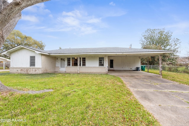 ranch-style house featuring brick siding, an attached carport, fence, a front yard, and driveway