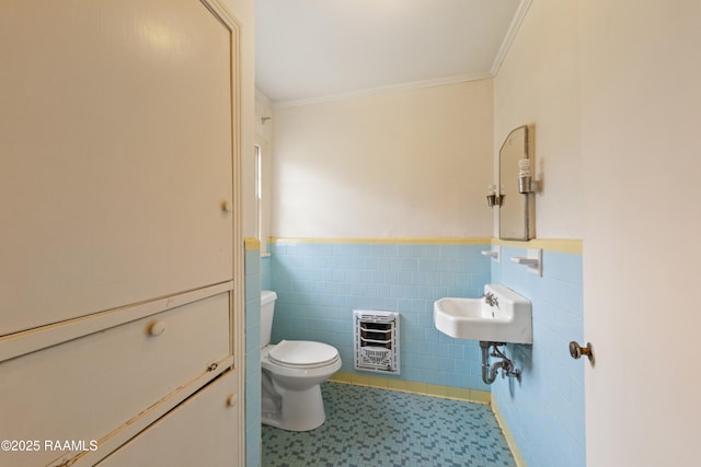 half bath with toilet, ornamental molding, wainscoting, heating unit, and tile walls