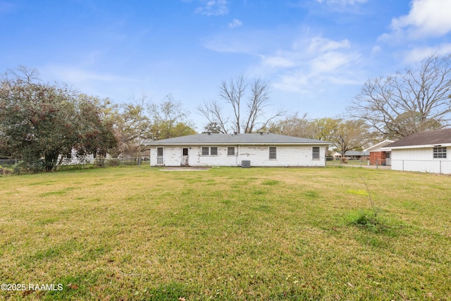 back of property featuring a lawn and fence