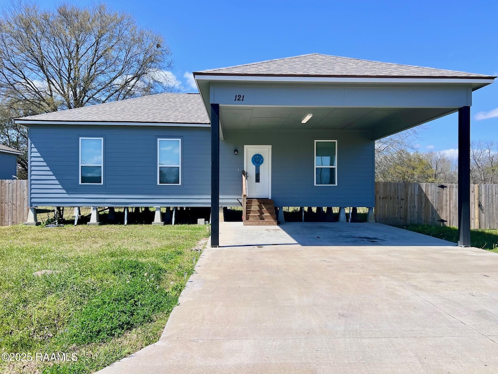 view of front of property with a shingled roof, concrete driveway, a front yard, and fence