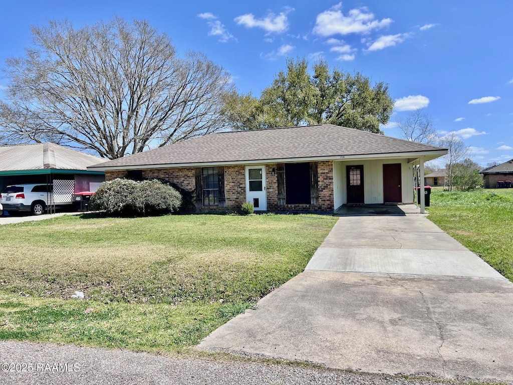 single story home featuring a carport, brick siding, concrete driveway, and a front yard