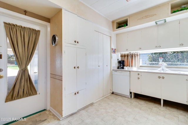 kitchen featuring light floors, dishwasher, light countertops, white cabinets, and a sink