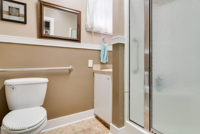 bathroom featuring a shower with shower door, toilet, vanity, and tile patterned floors