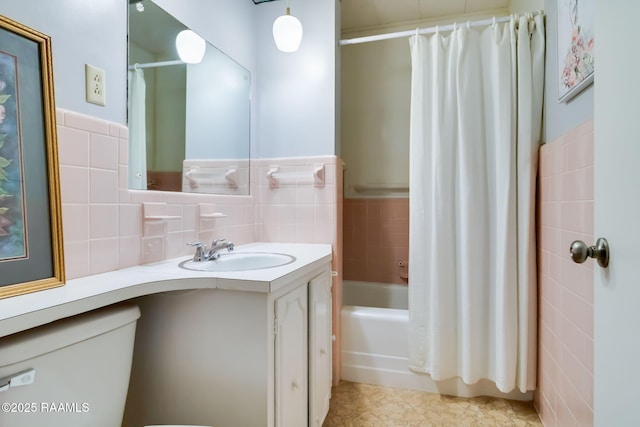 bathroom featuring a wainscoted wall, toilet, vanity, shower / bath combo, and tile walls