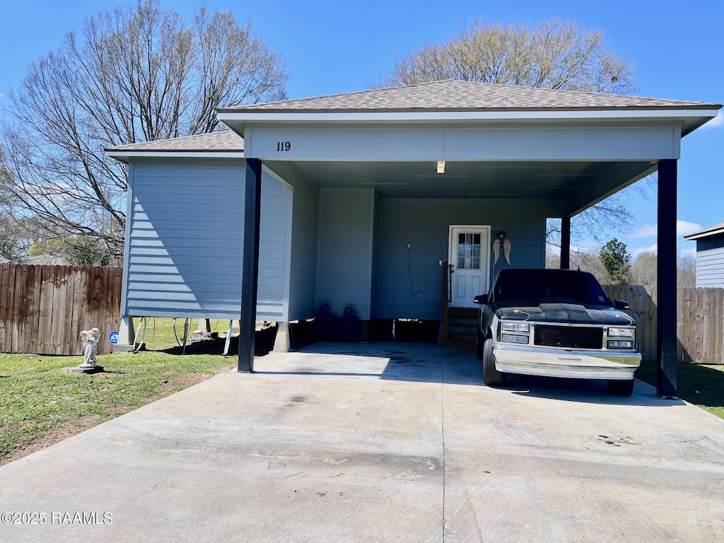 view of front facade with an attached carport, fence, driveway, and roof with shingles