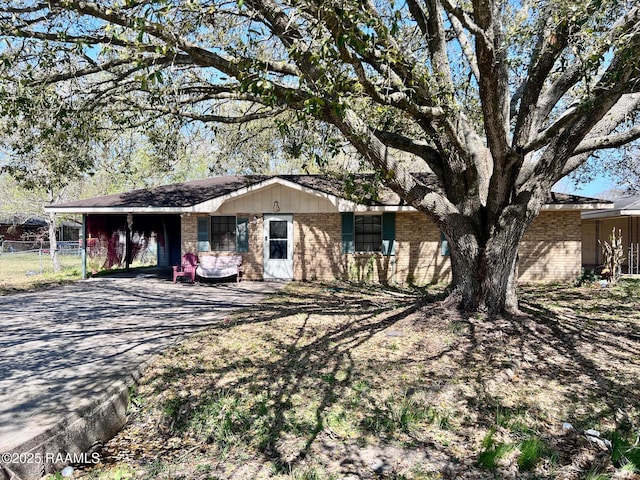 single story home featuring brick siding, fence, aphalt driveway, and a carport