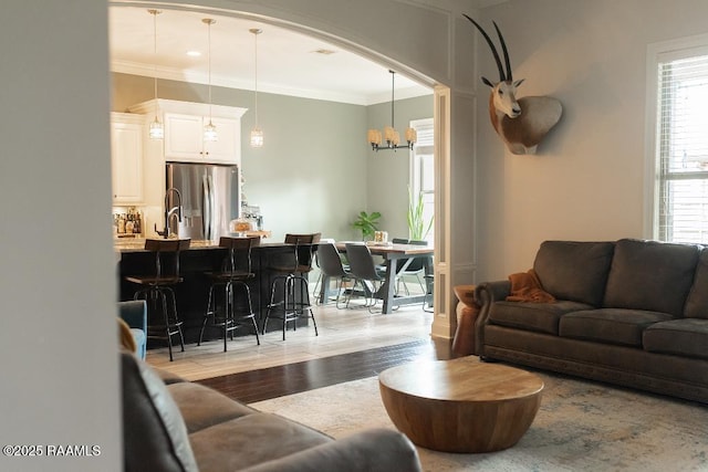 living area with a chandelier, light wood finished floors, and ornamental molding