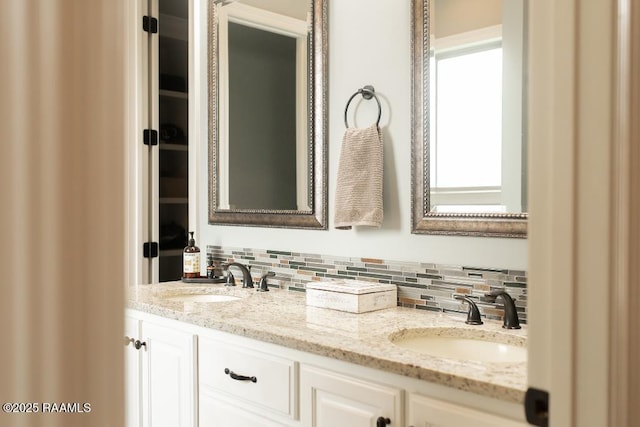 full bathroom with double vanity, backsplash, and a sink